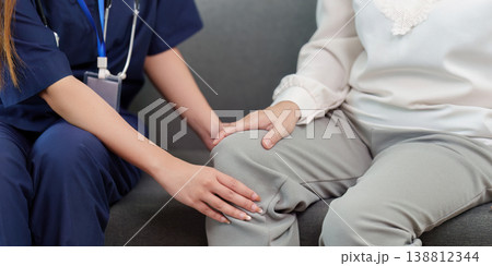 Nurse assisting elderly woman with knee pain Nurse assisting elderly woman with knee pain 138812344