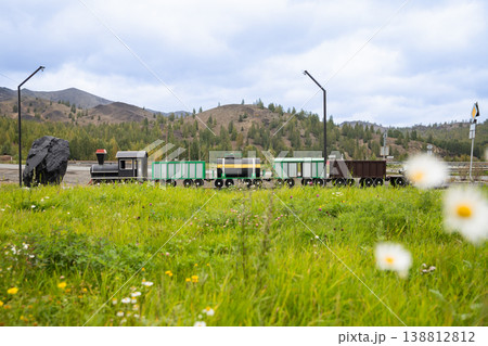 Old Soviet toy train with carriages, realistic model in the open air against the backdrop of mountains. Nostalgic memory, symbol of industry Old Soviet toy train with carriages, realistic model in the open air against the backdrop of mountains. Nostalgic memory, symbol of industry 138812812