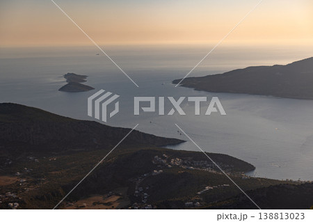 Golden sunset light bathes a rocky coastline and two small islands 138813023