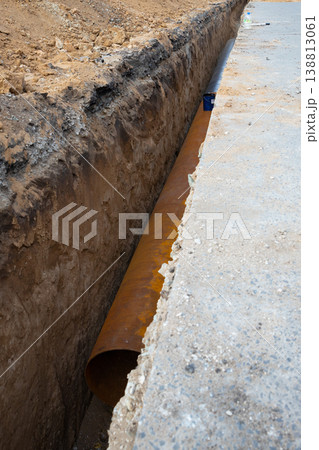 large diameter water pipe in a earthen trench under the asphalt street surface. Repair, renovation or replacement of municipal equipment in the city large diameter water pipe in a earthen trench under the asphalt street surface. Repair, renovation or replacement of municipal equipment in the city 138813061