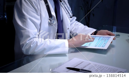 Medical doctor analyzing digital health records on a tablet computer, ensuring patient data management and secure care information in a modern clinic setting Medical doctor analyzing digital health records on a tablet computer, ensuring patient data management and secure care information in a modern clinic setting 138814514
