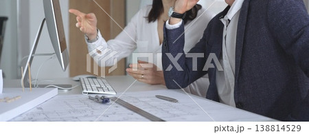 Architects collaborating on architectural project, discussing blueprints and design models on office table. Business and architecture concept Architects collaborating on architectural project, discussing blueprints and design models on office table. Business and architecture concept 138814529