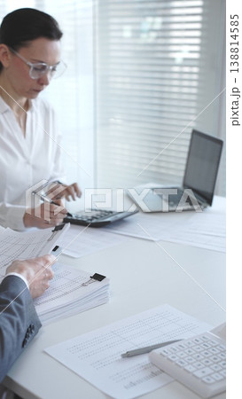 Professionals handling a large stack of documents and paperwork, signing a contract in a busy office. Audit and taxes in business 138814585