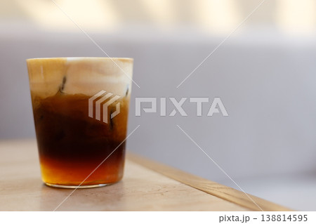 Cup of creation black coffee drink and orange juice on wooden table by the window. Cup of creation black coffee drink and orange juice on wooden table by the window. 138814595