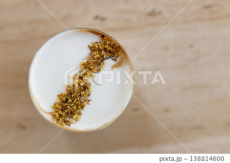 Cup of creation coffee drink and milk foam decorated with Osmanthus flower on wooden table by the window. 138814600