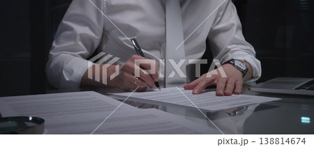 Business man signing a contract late in the office, closing a deal, or completing legal paperwork at deep night. Audit and overworking concepts Business man signing a contract late in the office, closing a deal, or completing legal paperwork at deep night. Audit and overworking concepts 138814674