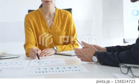 Business professionals gathered around conference table, reviewing financial charts, collaborating on strategic planning and corporate analysis 138814725