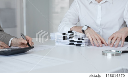 Accountants reviewing financial documents, calculating taxes, and preparing audit reports in a modern office environment. Audit and taxes in business Accountants reviewing financial documents, calculating taxes, and preparing audit reports in a modern office environment. Audit and taxes in business 138814870