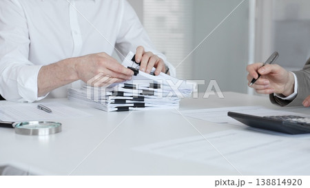 Professionals handling a large stack of documents and paperwork, signing a contract in a busy office. Audit and taxes in business 138814920