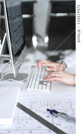 Architect working at desktop computer, checking blueprints and design plans for a new engineering project. Business and architecture concept Architect working at desktop computer, checking blueprints and design plans for a new engineering project. Business and architecture concept 138814972