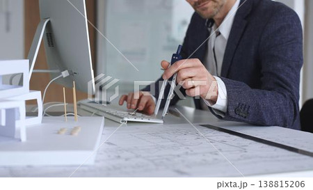 Professional architect drafting blueprints at a desk, holding a compass, focusing on structural plans and urban design. Business and architecture concept Professional architect drafting blueprints at a desk, holding a compass, focusing on structural plans and urban design. Business and architecture concept 138815206