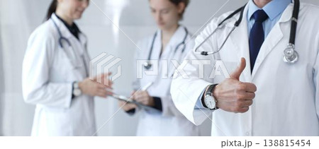 Doctor giving thumbs up sign for medical approval while standing with health practitioners, symbolizing trust in healthcare, patient well being, and successful treatment Doctor giving thumbs up sign for medical approval while standing with health practitioners, symbolizing trust in healthcare, patient well being, and successful treatment 138815454