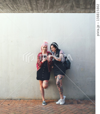 Friends, smartphone and students, women against wall background with social media and check chat online. Young female people on college campus, using phone and app, punk fashion and communication 138815802