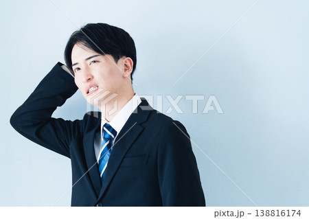 頭を抱えるスーツ姿の若い男性 138816174