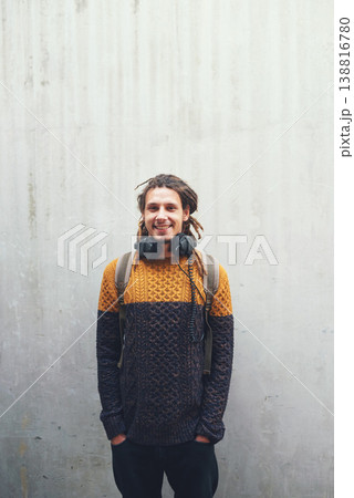 Portrait, smile and man with streetwear, casual outfit and stylish guy against a wall background. Male person, hipster and fashion with headphones, Canada or confident with positive mindset and music Portrait, smile and man with streetwear, casual outfit and stylish guy against a wall background. Male person, hipster and fashion with headphones, Canada or confident with positive mindset and music 138816780