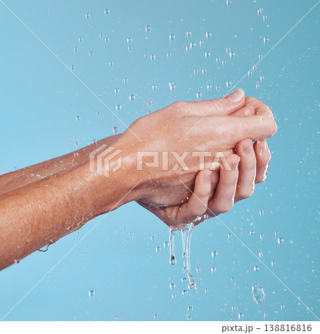 Water drops, hygiene and a person washing hands in studio on a blue background for cleaning or hydration. Beauty, wellness and skincare with a splash in the bathroom for sustainability or health Water drops, hygiene and a person washing hands in studio on a blue background for cleaning or hydration. Beauty, wellness and skincare with a splash in the bathroom for sustainability or health 138816816