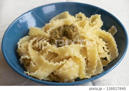 Italian mafaldine pasta with basil pesto and fresh parsley in blue bowl Italian mafaldine pasta with basil pesto and fresh parsley in blue bowl 138817840