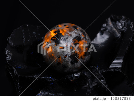 Macro View of Polished Oranges and Black Stone Sphere Resting on Jagged Obsidian Glass Fragments 138817858