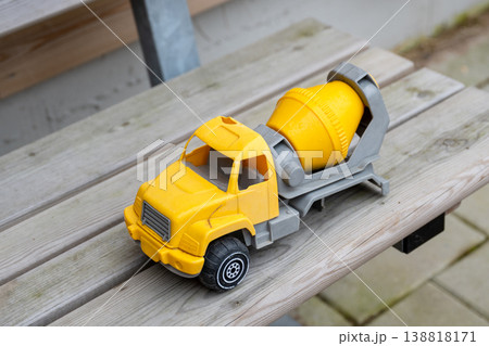 Yellow toy cement mixer truck on wooden bench with blurred rustic background 138818171