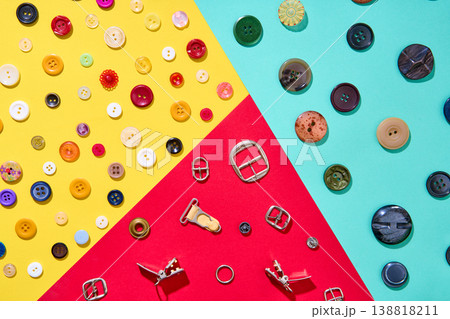 Colorful sewing accessories composition on geometric background, buttons and metal buckles 138818211
