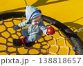 Little girl in sunglasses sits on a rope swing at the playground 138818657