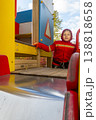 Child with red raincoat of firefighter clings to a rope in a playground during rain. 138818658