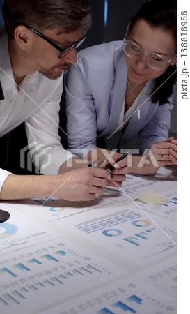 Business colleagues collaborating on financial reports, analyzing market data and corporate strategy by reviewing charts and graphs on a table in an office meeting Business colleagues collaborating on financial reports, analyzing market data and corporate strategy by reviewing charts and graphs on a table in an office meeting 138818988