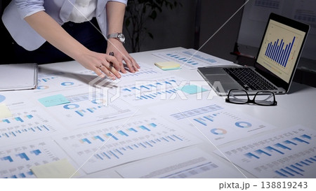 Person analyzing financial data, reviewing business analytics reports, using a laptop with charts, and planning corporate strategy with spreadsheets and investment figures 138819243