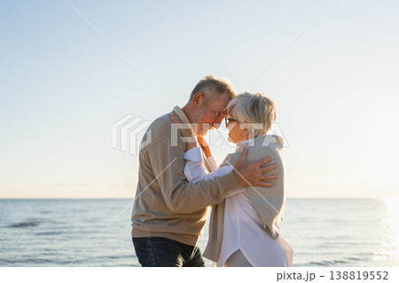 Senior mature couple hugging enjoying outdoor recreation walking on beach. Old husband wife embracing with tenderness love enjoying sweet bonding. Grandmother grandfather together. Family moment love Senior mature couple hugging enjoying outdoor recreation walking on beach. Old husband wife embracing with tenderness love enjoying sweet bonding. Grandmother grandfather together. Family moment love 138819552