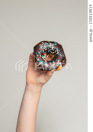 Chocolate Donut in human hand. Tasty doughnut, sweet dessert food Chocolate Donut in human hand. Tasty doughnut, sweet dessert food 138819614