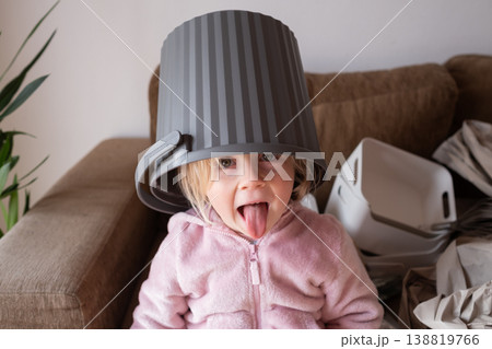 Funny 4 year old girl playing and putting a new trash can on her head Funny 4 year old girl playing and putting a new trash can on her head 138819766
