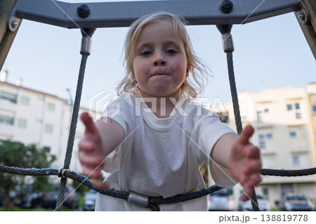 Active 4 year old girl climbing up a rope ladder at the playground Active 4 year old girl climbing up a rope ladder at the playground 138819778