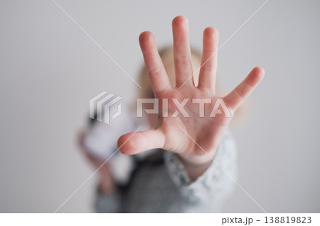 Serious 4 year old girl showing stop gesture with her outstretched palm toward the camera Serious 4 year old girl showing stop gesture with her outstretched palm toward the camera 138819823