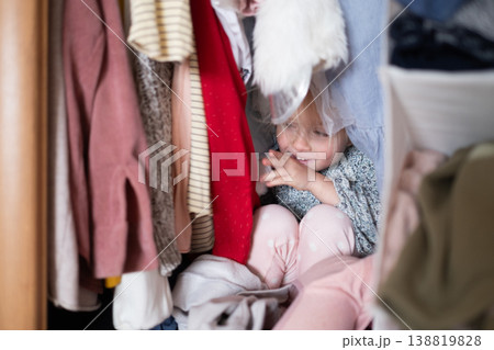 Little 4 Year Old Caucasian Girl Playing Hide-and-Seek Inside a Cluttered Clothes Wardrobe Little 4 Year Old Caucasian Girl Playing Hide-and-Seek Inside a Cluttered Clothes Wardrobe 138819828