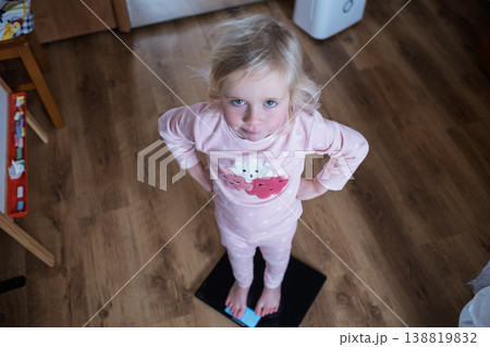Cute 4 year old Caucasian girl standing on weighing scales Cute 4 year old Caucasian girl standing on weighing scales 138819832