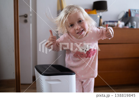 Independent 4 year old girl turning on a modern air dehumidifier to control humidity in her room 138819845