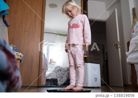 Cute 4 year old Caucasian girl standing on weighing scales Cute 4 year old Caucasian girl standing on weighing scales 138819856