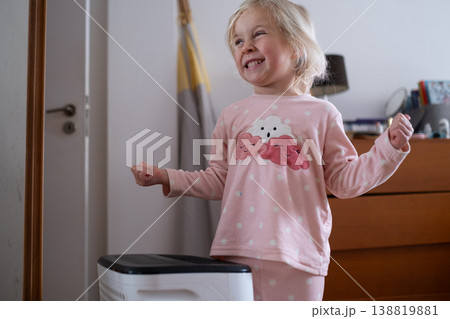 Independent 4 year old girl turning on a modern air dehumidifier to control humidity in her room 138819881