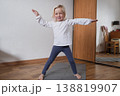 Cute 4-year-old child standing on yoga mat and stretching arms. 138819907
