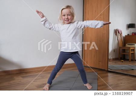 Cute 4-year-old child standing on yoga mat and stretching arms. Cute 4-year-old child standing on yoga mat and stretching arms. 138819907