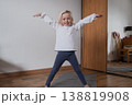 Cute 4-year-old child standing on yoga mat and stretching arms. 138819908