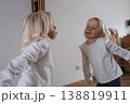 Funny little girl making faces in front of the mirror. 138819911