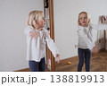 Funny little girl making faces in front of the mirror. 138819913
