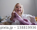 Laughing little girl sitting on the bed in a cozy bedroom. 138819936