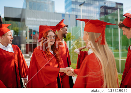 Graduates congratulating each other with handshake during university graduation ceremony. Graduates congratulating each other with handshake during university graduation ceremony. 138819983