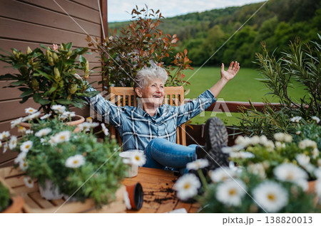 Senior woman with coffee sitting on terrace, resting after gardening. Senior woman with coffee sitting on terrace, resting after gardening. 138820013