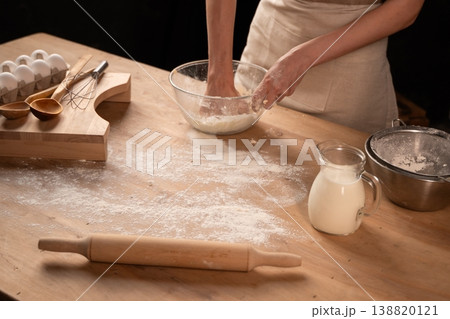 Person kneading dough for baking homemade bread on a rustic wooden table with flour, milk, and eggs Person kneading dough for baking homemade bread on a rustic wooden table with flour, milk, and eggs 138820121