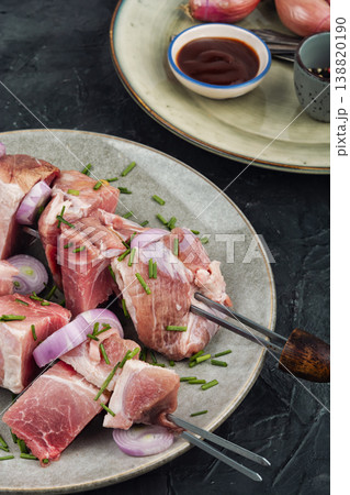 Raw pork skewers with onion and herbs on plate 138820190