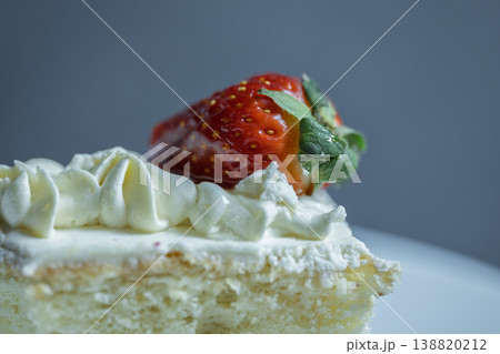 Close up of a moist sponge cake topped with rich whipped cream and a ripe red strawberry Close up of a moist sponge cake topped with rich whipped cream and a ripe red strawberry 138820212