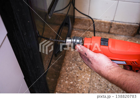 Homeowner drilling into oven door during kitchen repair Homeowner drilling into oven door during kitchen repair 138820783